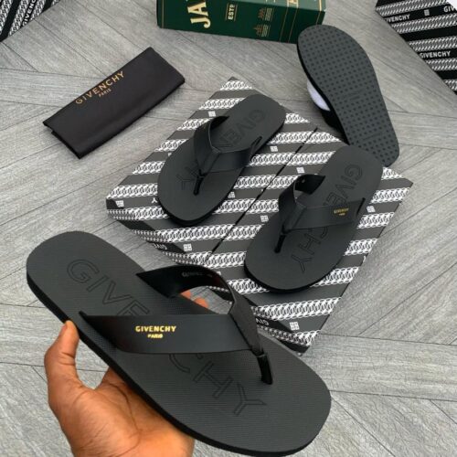 A hand holding a pair of black Givechy shoes with gold lettering, showcasing the brand's signature design and quality.