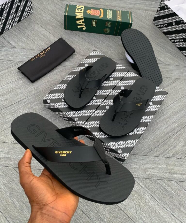 A hand holding a pair of black Givechy shoes with gold lettering, showcasing the brand's signature design and quality.